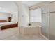 Bathroom featuring a soaking tub, tile flooring, a glass-enclosed shower, and a partial view to the main bedroom at 5619 Bear Stone Run, Oviedo, FL 32765