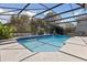Screened-in pool boasts blue tile accents and a refreshing view of the natural surroundings at 5619 Bear Stone Run, Oviedo, FL 32765