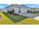 Light blue home featuring a two-car garage, beautiful landscaping, and manicured green lawn at 7369 Sw 77Th Ave, Ocala, FL 34481