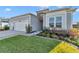 Light blue home featuring a two-car garage and landscaped garden with lush green lawn at 7369 Sw 77Th Ave, Ocala, FL 34481