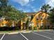 Two story unit with yellow exterior and a parking area with palm trees and nice landscaping at 8843 Villa View Cir # 14-205, Orlando, FL 32821