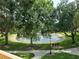 Picturesque view of the pond surrounded by mature trees, verdant lawns, and inviting bench seating at 8843 Villa View Cir # 14-205, Orlando, FL 32821