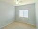 This is a simple bedroom with neutral tones, carpet floors, ceiling fan, and a bright window at 9620 Doris Ln, Orlando, FL 32829