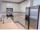 Well-lit kitchen with stainless steel appliances, light countertops, and matching cabinetry at 9620 Doris Ln, Orlando, FL 32829