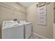 Functional laundry room with a washer, dryer, wire rack shelf and tile flooring at 11880 Sonnet Ave, Orlando, FL 32832