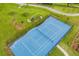 Aerial view of blue community tennis court with surrounding green space, path, and play hill at 11880 Sonnet Ave, Orlando, FL 32832