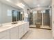 Modern bathroom featuring double sinks, a large framed mirror, and multiple glass-enclosed walk-in showers with gray tile at 1468 Fairview Cir, Reunion, FL 34747