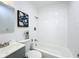 Refreshed bathroom with stylish white tiles, gray vanity, and artwork at 1503 Holly Rd, Lakeland, FL 33801