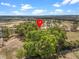 Lush, green trees surround this property, highlighted by a red pin, against a backdrop of clear blue skies at 16510 Quarter Horse Ct, Montverde, FL 34756