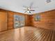 Light-filled bedroom features wood paneling, hardwood floors, a ceiling fan, and French doors overlooking the yard at 16510 Quarter Horse Ct, Montverde, FL 34756