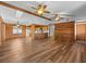 Open living space showcasing wood-paneled walls, exposed ceiling beams, ceiling fans, and seamless flow to kitchen at 16510 Quarter Horse Ct, Montverde, FL 34756