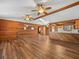 Bright living room with wood-paneled walls, exposed beams, ceiling fans, and an open transition to the kitchen at 16510 Quarter Horse Ct, Montverde, FL 34756