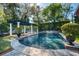 Scenic backyard view of a sparkling pool featuring a waterfall, pergola, and manicured garden at 1911 Stonehurst Rd, Winter Park, FL 32789