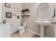 Chic powder room with a pedestal sink, decorative shelves, and stylish wall art at 2342 Gold Dust Dr, Minneola, FL 34715