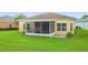 Rear exterior showcasing a home with a screened lanai and lush, green lawn at 253 Lake Cassidy Dr, Kissimmee, FL 34759