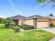 Inviting single-story residence with a neutral-toned exterior, stone detailing, manicured landscaping and brick paver driveway at 253 Lake Cassidy Dr, Kissimmee, FL 34759