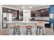 A kitchen island with bar stool seating complemented by dark brown cabinetry at 3242 Irish Peach Dr, Winter Garden, FL 34787