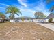 Front view of the home, featuring a palm tree, a long driveway, and a white picket fence at 3764 Pinehurst St, Deltona, FL 32738