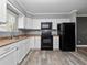 Well-lit kitchen featuring white cabinets, black appliances, and wood-look flooring at 3764 Pinehurst St, Deltona, FL 32738