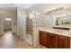 Bathroom featuring custom glass block shower, cabinets, and tile floors at 4724 Sable Ridge Ct, Leesburg, FL 34748