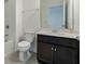 Bathroom with white tiled shower-tub combo, dark cabinets, and a large mirror reflecting natural light at 4796 Riverwalk Dr, St Cloud, FL 34771