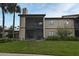 Exterior view of a two-story condominium featuring a screened-in balcony with palm trees and green grass at 609 Gallery Dr # 2, Winter Park, FL 32792