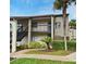 Two story condo building with neutral paint, dark railings, tropical plants, and stairs leading to the second level entrance at 609 Gallery Dr # 2, Winter Park, FL 32792