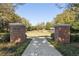 A gated community entrance with brick pillars, a fountain, lush landscaping, and a paved walkway at 6424 Cartmel Ln, Windermere, FL 34786