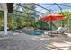 The in-ground swimming pool with waterfall, screened-in lanai, umbrella, lounge chairs, and brick pavers at 6424 Cartmel Ln, Windermere, FL 34786