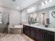 Bright bathroom featuring double vanities, bathtub and glass enclosed shower with neutral color tones and modern fixtures at 753 Daybreak Pl, Longwood, FL 32750