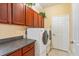 Laundry room with front loading washer and dryer, granite counters, and wooden cabinets at 755 Country Charm Cir, Oviedo, FL 32765