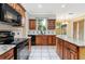 Bright kitchen with granite countertops, wooden cabinets and black appliances overlooking the backyard at 9400 Southern Garden Cir, Altamonte Springs, FL 32714