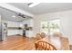 Dining room features wood-look floors, ceiling fan, wood table set, and a view into the kitchen with white cabinets at 10115 E Highway 316, Fort Mc Coy, FL 32134