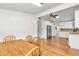 Dining room features wood-look floors, ceiling fan, wood table set, and a view into the kitchen with white cabinets at 10115 E Highway 316, Fort Mc Coy, FL 32134