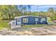 Exterior view of blue house featuring a ramp, bright door, and well-maintained landscaping at 10115 E Highway 316, Fort Mc Coy, FL 32134