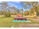 Car parked next to wooden garage on a grassy lot with mature trees offering shade and privacy at 10115 E Highway 316, Fort Mc Coy, FL 32134