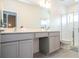 This bathroom features double sinks, gray cabinets, quartz countertops and a glass shower at 10443 Ebb Tide Ln, Orlando, FL 32821