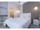 This bedroom features white bedding, bedside table, stylish light fixture, walk-in closet and bathroom at 10443 Ebb Tide Ln, Orlando, FL 32821