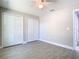 Spacious bedroom with ceiling fan, light gray walls, wood-look tile floors, and double closet with white doors at 11364 Cardiff Dr, Orlando, FL 32837