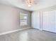 A cozy bedroom with a ceiling fan, light gray walls, wood-look tile floors, a window, and closet with white doors at 11364 Cardiff Dr, Orlando, FL 32837