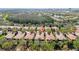 Expansive aerial view showcases a neighborhood of homes with terracotta roofs and a tranquil lake in the background at 11916 Fiore Dr, Orlando, FL 32827