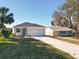 A cozy home exterior featuring a well-kept lawn, a driveway, and a two-car garage at 13820 Adams St, Grand Island, FL 32735