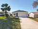 Charming single-story home showcasing a manicured lawn, palm tree, and attached two-car garage at 13820 Adams St, Grand Island, FL 32735