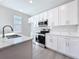 Kitchen features white cabinets, stainless steel appliances, and natural light at 13820 Adams St, Grand Island, FL 32735