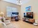 Cozy living room with a tan couch, wood floors, a television, a desk and a large window at 1421 Arbitus Cir, Oviedo, FL 32765
