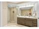 Bright bathroom with a double vanity, large mirror, and glass enclosed shower with decorative tile at 16300 County Road 455 # 401, Montverde, FL 34756