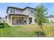 Home's backyard with covered patio, well maintained lawn and young tree in a modern two-story home with light gray siding at 16354 Silver Grove Blvd, Winter Garden, FL 34787