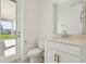 Bathroom features a toilet, door to the patio, and a vanity with white cabinets and a silver faucet at 16354 Silver Grove Blvd, Winter Garden, FL 34787