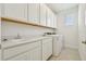 Well-lit laundry room with white cabinets, sink, and a modern washing machine at 16354 Silver Grove Blvd, Winter Garden, FL 34787