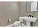 A half bathroom with wallpaper, a mirror, and a pedestal sink at 17300 Pesce Loop, Montverde, FL 34756